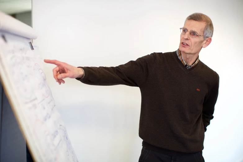 a man standing in front of a white board, a picture, by Jakob Gauermann, with pointing finger, petri rahkola, standing sideways, slightly blurry