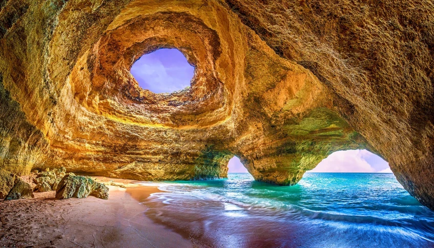 a view of the ocean from inside a cave, a photo, shutterstock, portugal, round windows, details and vivid colors, falling sand inside