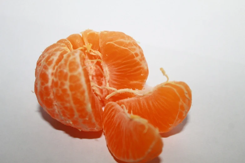 a peeled orange sitting on top of a white surface, a macro photograph, berries inside structure, discovered photo, istockphoto, orange color