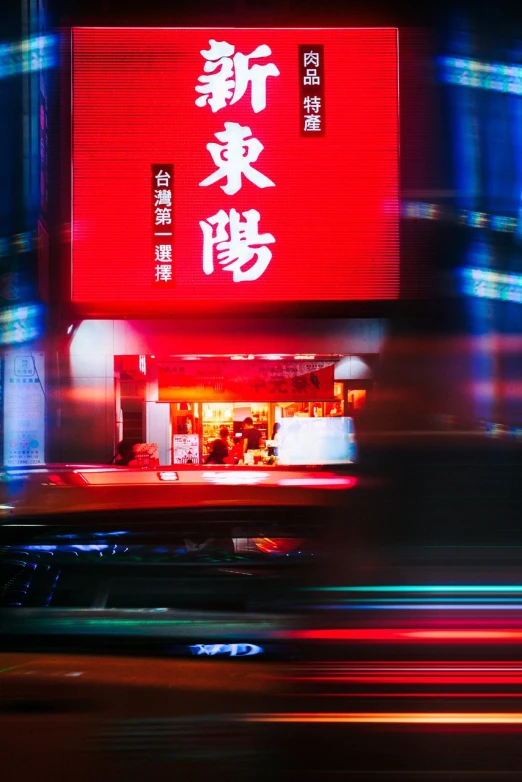 a red sign on the side of a building, a picture, by Patrick Ching, pexels contest winner, busy night, cover photo portrait of du juan, exiting store, 1128x191 resolution