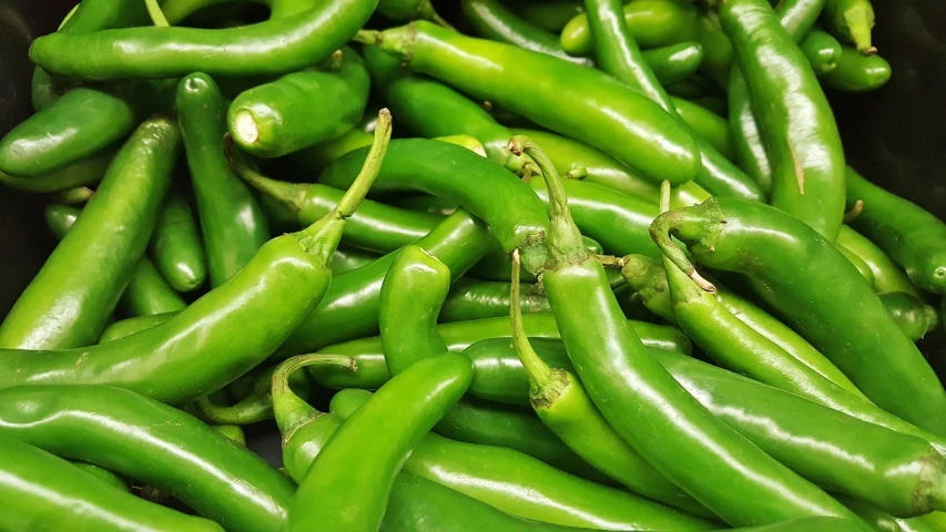 a pile of green peppers sitting on top of a table, a picture, pexels, happening, chili, background image, 🦩🪐🐞👩🏻🦳, new mexico