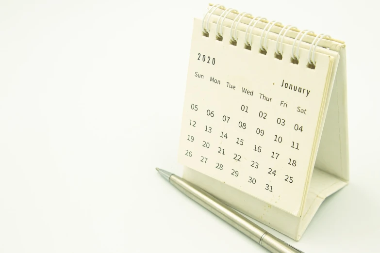 a calendar sitting on top of a desk next to a pen, by Awataguchi Takamitsu, happening, white background, imet2020, ( ready - made ), ivory