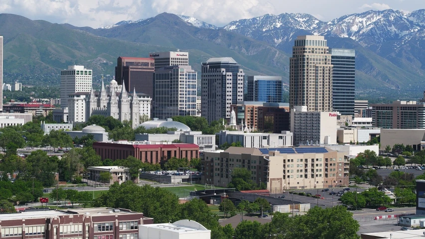 a view of a city with mountains in the background, a picture, by Randall Schmit, on a bright day, white buildings, central hub, taken in the late 2010s