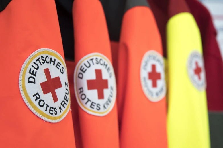 a row of life jackets with a red cross sticker on them, a photo, by Dietmar Damerau, shutterstock, tech robes, munich, 💣 💥, 2 0 1 6