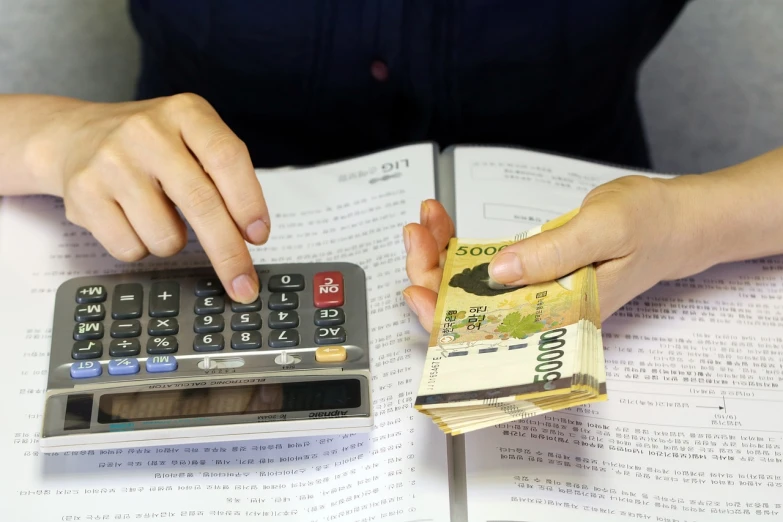 a person sitting at a table with a calculator and money, mingei, hong soonsang, detailed zoom photo, full res, blog-photo