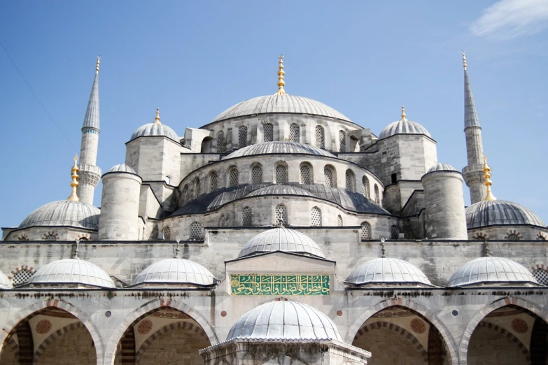 a large white building with a green sign in front of it, inspired by Osman Hamdi Bey, shutterstock, hurufiyya, interior of a marble dome, black domes and spires, blue, view from ground