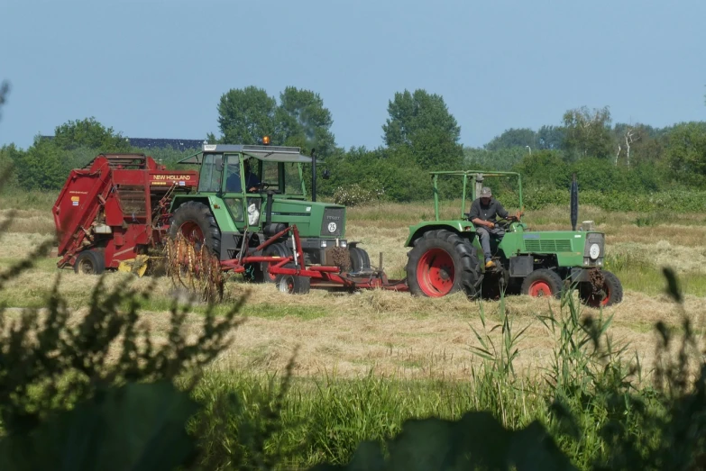 a couple of tractors that are sitting in the grass, by Schelte a Bolswert, mowing of the hay, red green, leon tukker, dennis velleneuve