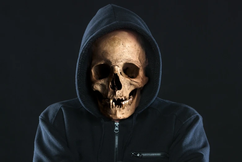 a man in a hoodie with a skull on his face, a portrait, shutterstock, he is wearing a black t-shirt, humanoid face, zippered opening in skull, facebook profile picture