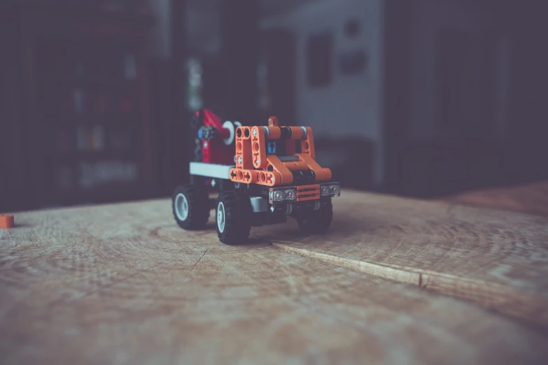 a toy truck sitting on top of a wooden table, pexels contest winner, constructivism, lego movie style, micro - hurricane, orange body, shot with sigma f / 4. 2