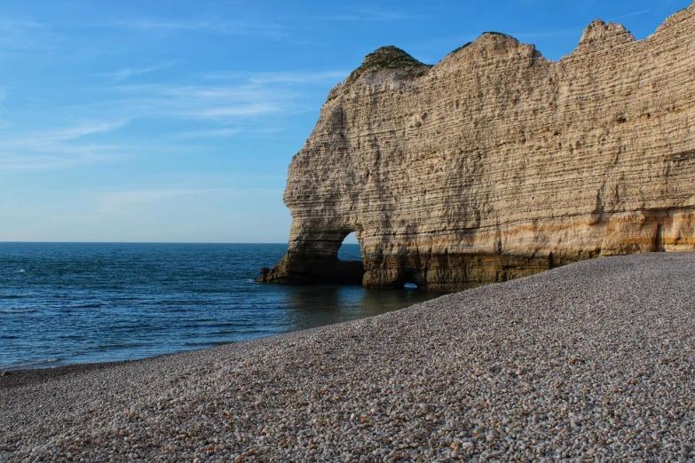 a large rock formation on a beach next to the ocean, by Etienne Delessert, shutterstock, les nabis, chalk cliffs above, detailed 4 k photo, france, stock photo