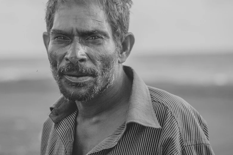 a black and white photo of a man with a beard, by Rajesh Soni, pexels contest winner, fine art, near the sea, detailed faces, desaturated, half onesided smile