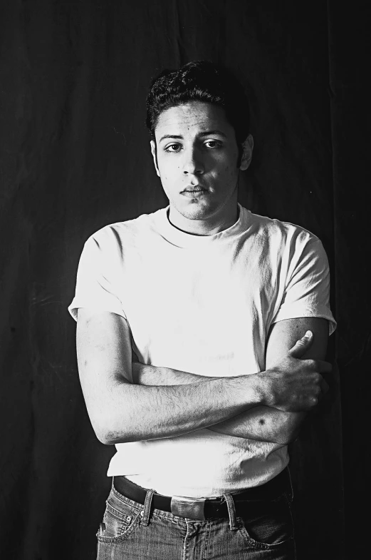 a black and white photo of a man with his arms crossed, a portrait, inspired by Alejandro Obregón, pete davidson, bruce springsteen, mid length portrait photograph, 2000s photo