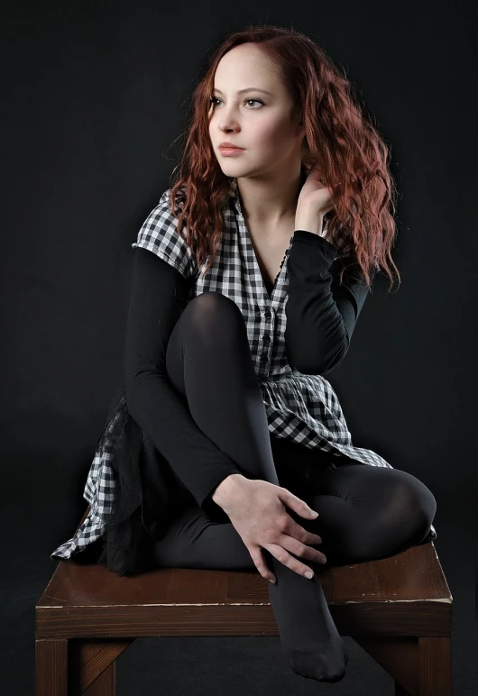 a woman sitting on top of a wooden bench, a portrait, inspired by irakli nadar, shutterstock, art photography, plaid tights, sullen old maid ( redhead, girl in studio, a beautiful teen-aged girl
