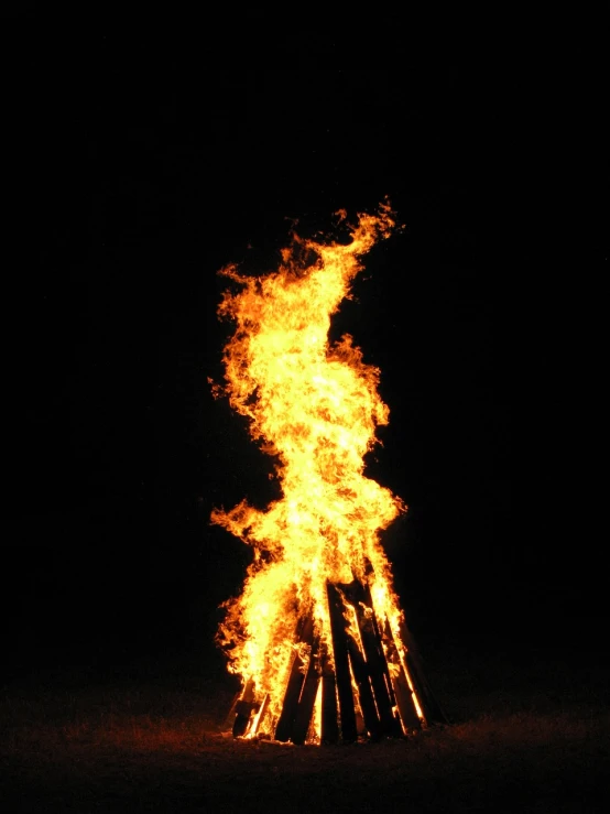 a bonfire is lit up in the dark, a photo, by Rodney Joseph Burn, fuming effigy, large tall, wikimedia, ryan mcginley