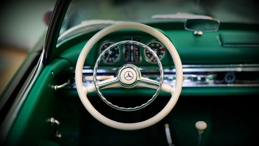 a close up of a steering wheel on a green car, a portrait, inspired by Harry Haenigsen, unsplash, retrofuturism, mercedez benz, photorealism. trending on flickr, 1957, scale model photography