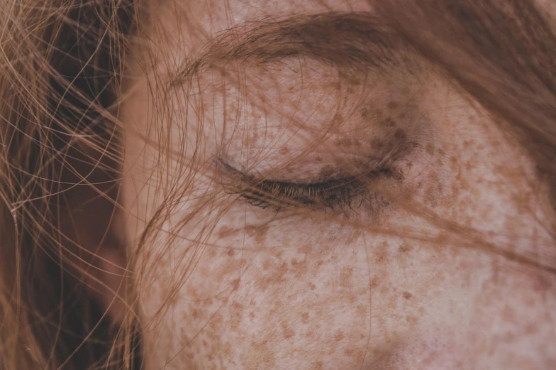 a close up of a woman's face with freckles, inspired by Elsa Bleda, with closed eyes, 40 years old women, 33mm photo, hair covering eyes