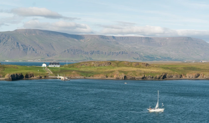 a sailboat in a body of water with mountains in the background, by Hallsteinn Sigurðsson, shutterstock, hospital in background, green pastures stretch for miles, high res photo, cliffside