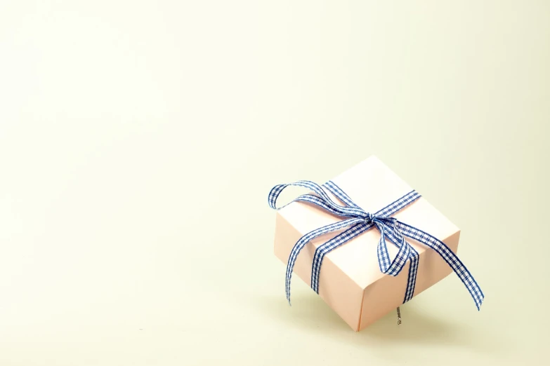 a small white gift box with a blue ribbon, a picture, pixabay, minimalism, light pink tonalities, analogue, cream, wide wide shot