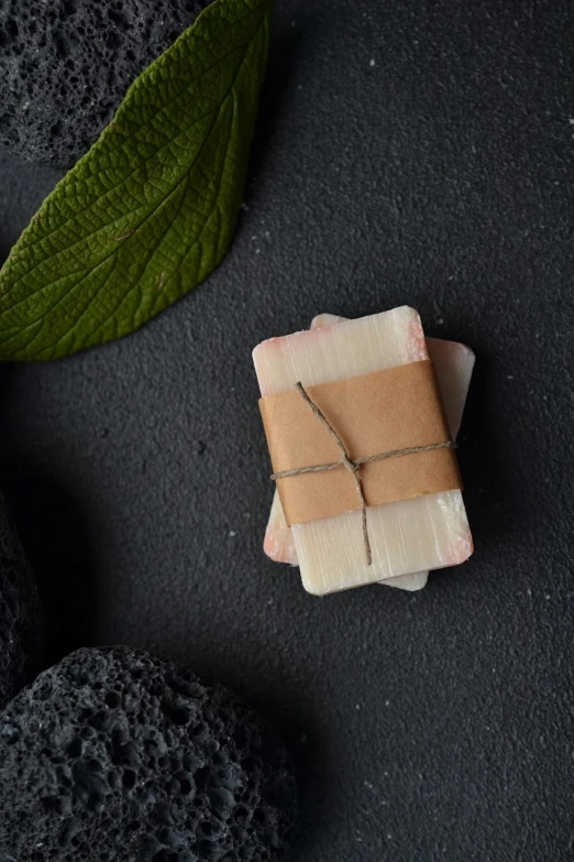 a piece of wax sitting on top of a piece of paper, a marble sculpture, by Dóra Keresztes, unsplash, bark for skin, black white pastel pink, carved soap, against dark background