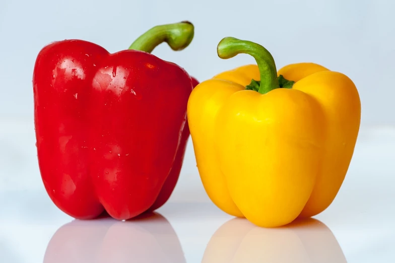 a couple of peppers sitting next to each other, a picture, pixabay, crisp colors, product photography, taken with canon 8 0 d, red-yellow colors