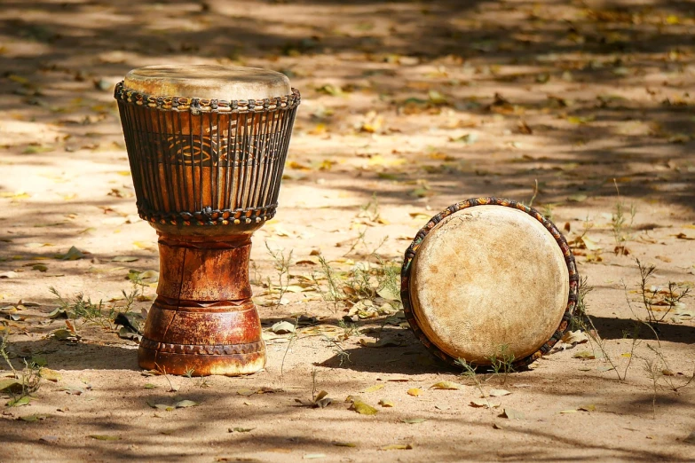 a couple of drums sitting on top of a sandy ground, shutterstock, dau-al-set, intricate detail and quality, 🌻🎹🎼, tamborine, lush surroundings