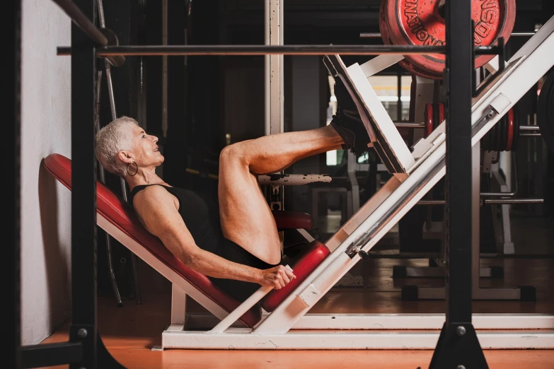 a man sitting on a bench in a gym, a photo, figuration libre, an old lady with red skin, detailed shot legs-up, 5 5 yo, high res photo