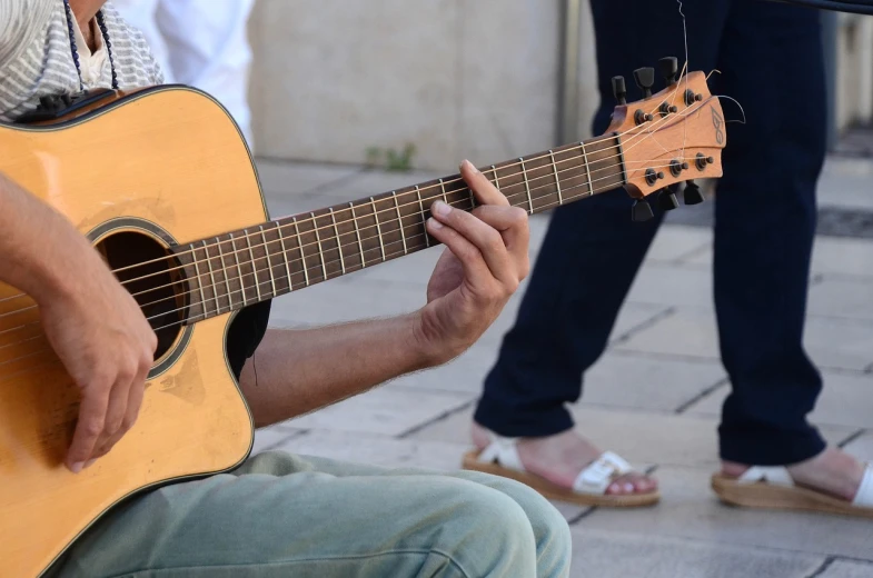 a close up of a person playing a guitar, by Niko Henrichon, pixabay, realism, on the street, in a square, costa blanca, getty images