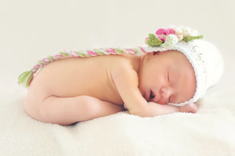 a baby sleeping on top of a white blanket, inspired by Anne Geddes, pexels, it's wearing a cute little hat, flower power, istockphoto, full-body