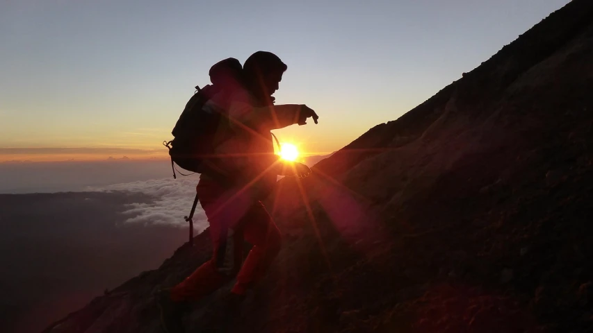 a man climbing up the side of a mountain at sunset, a picture, sumatraism, mt. fuji, photo taken in 2018, pointing to heaven, takumi fujiwara