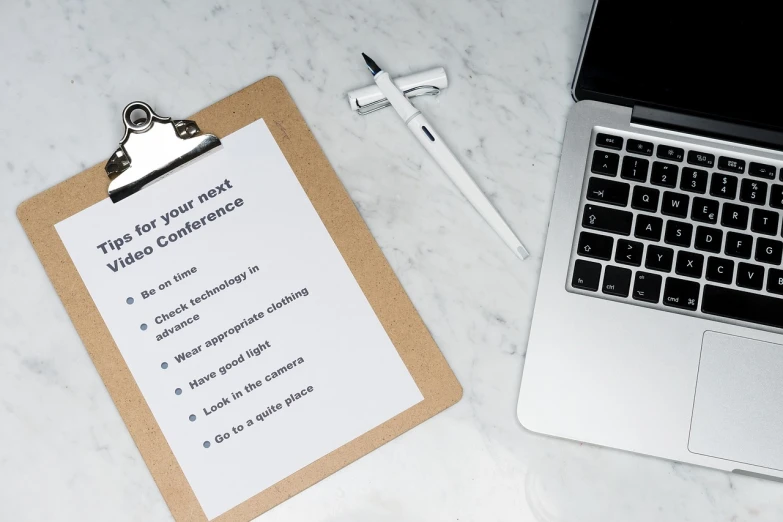 a clipboard sitting on top of a desk next to a laptop, by Robbie Trevino, pexels, with lots of text and icons, on white paper, video footage, simple clean lines