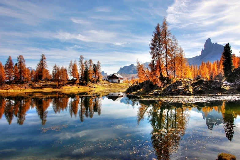 a body of water surrounded by trees and mountains, a picture, by Gabor Szikszai, shutterstock, romanticism, hut, autumn season, italy, marvellous reflection of the sky