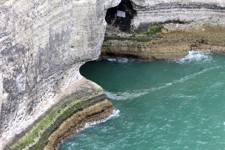 a man standing on top of a cliff next to a body of water, by Simon Marmion, les nabis, empty bathhouse hidden in a cave, northern france, afp, doves flying into the portal