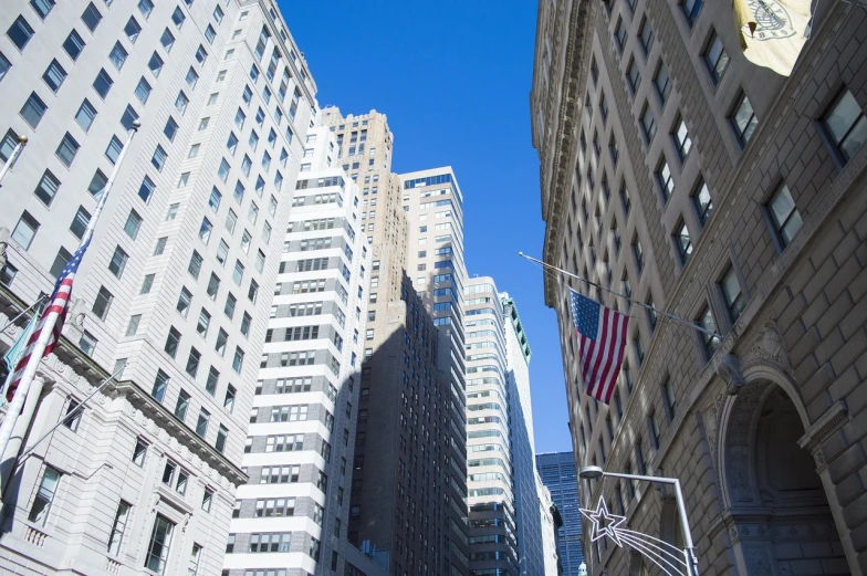 a city street filled with lots of tall buildings, a photo, by Robert Medley, shutterstock, wall street, dynamic low angle shot, on a bright day, usa-sep 20