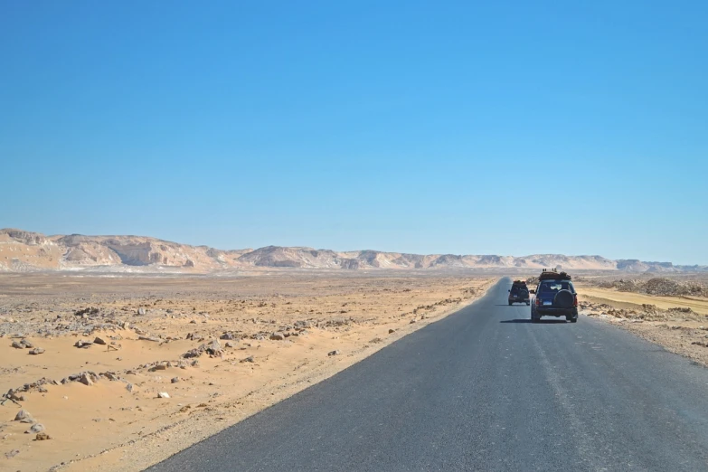 a car driving down the middle of a desert road, les nabis, egyptian landscape, wanderers traveling from afar, wide scene, high res photo