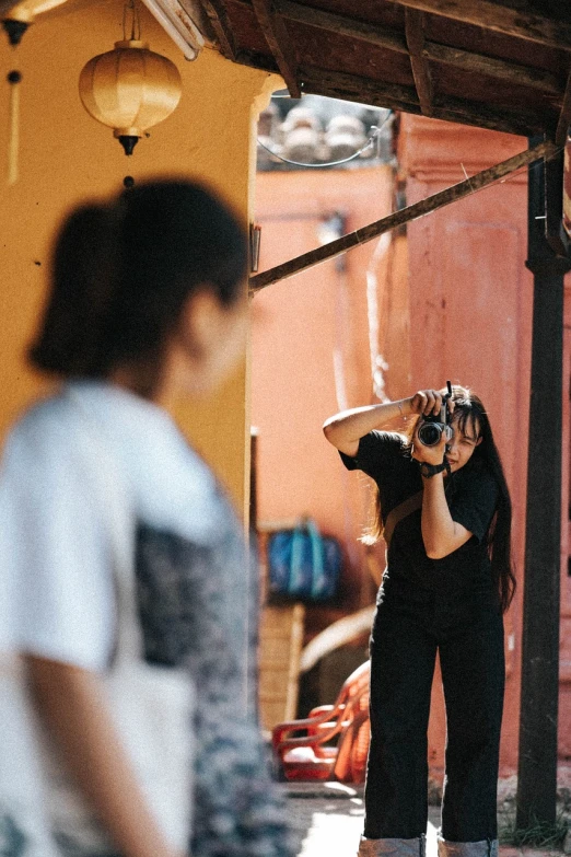 a woman taking a picture of a man with a camera, by Andrée Ruellan, action pose, in an alley, in front of an orange background, looking in a mirror