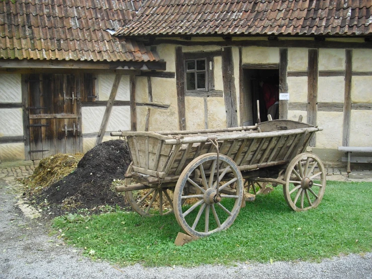 a wooden wagon sitting in front of a building, by Sigmund Freudenberger, flickr, renaissance, outside in a farm, soil, medieval architecture, from side