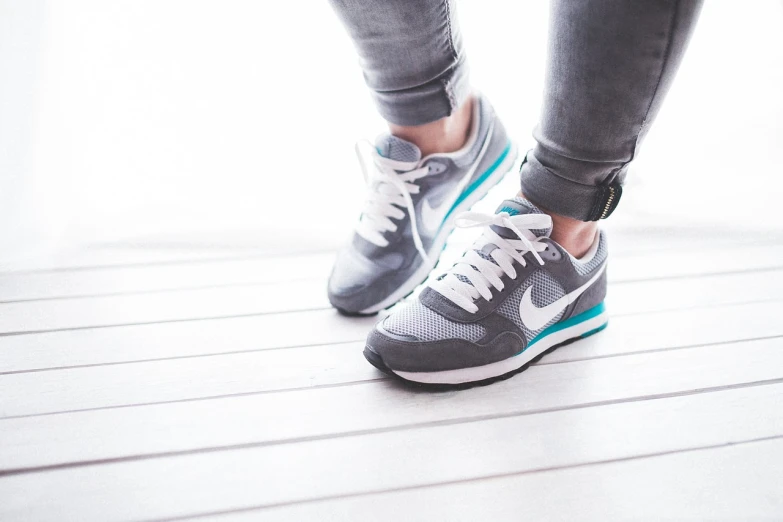 a close up of a person's shoes on a wooden floor, blue and grey, running shoes, annie leibowit, carefree