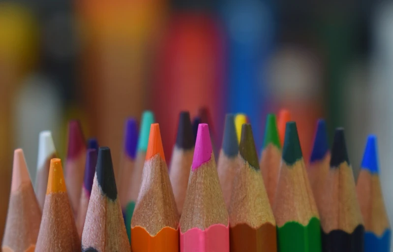 a close up of a bunch of colored pencils, a picture, by Edward Corbett, pexels, background blur bokeh!!, pink and orange colors, view from the bottom, educational