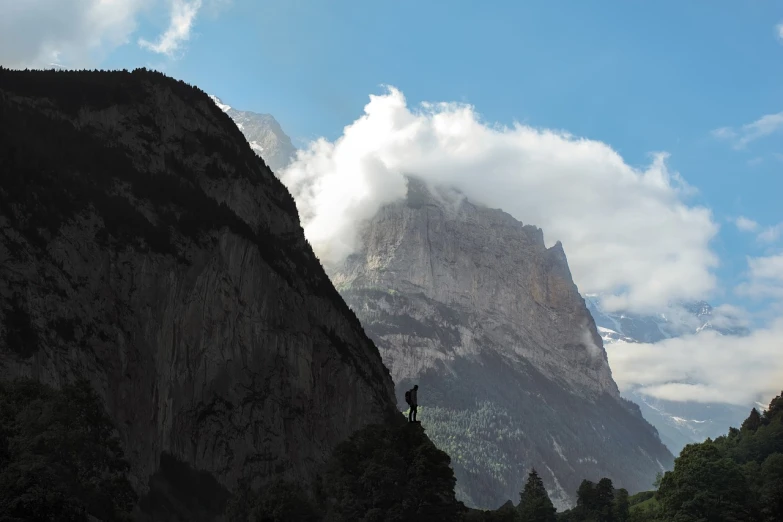 a bird is perched on the side of a mountain, a picture, figuration libre, lauterbrunnen valley, giant clouds, strong silhouette, a wide full shot