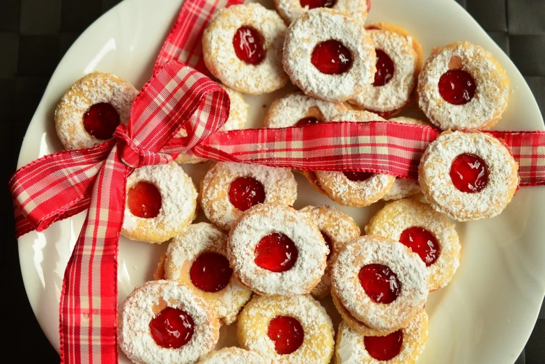 a white plate topped with cookies covered in powdered sugar, inspired by József Koszta, pixabay, dau-al-set, white red, rondel, rubies, austro - hungarian