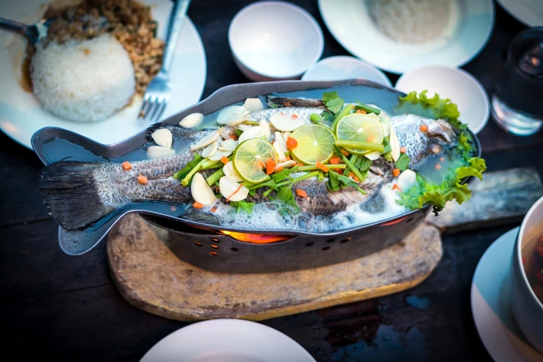 a fish sitting on top of a wooden cutting board, a photo, by Sam Dillemans, shutterstock, dau-al-set, thai, restaurant menu photo, silver platter, pot