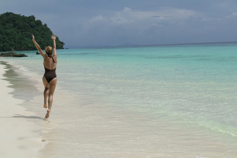 a woman jumping in the air on a beach, a photo, by Thomas Baines, flickr, sumatraism, white beaches, banner, tiffany, distant - mid - shot