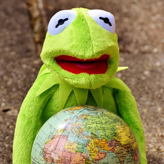 a close up of a stuffed animal holding a globe, inspired by Károly Brocky, pexels, plein air, portrait of kermit the frog, istockphoto, avatar image, tourist photo