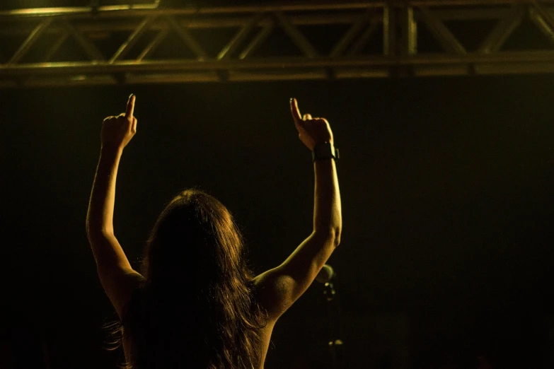 a woman holding her hands up in the air, a picture, by Mathias Kollros, figuration libre, stoner metal concert, banner, womanhood”, photo taken on a nikon