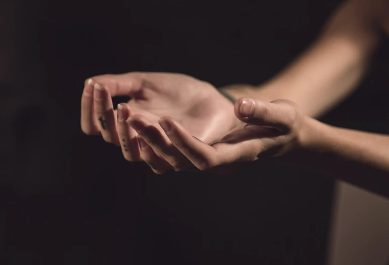 a close up of a person holding something in their hands, by Raphaël Collin, shutterstock, visual art, on a dark background, spiritual feeling, repetitiveness, real human female hand