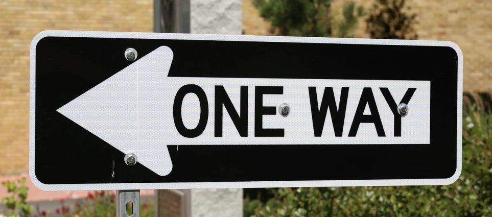 a one way sign in front of a brick building, by Jon Coffelt, pixabay, upon a peak in darien, shot on 1 5 0 mm, half done, banner