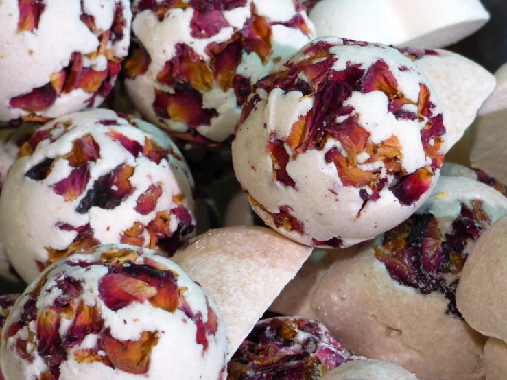 a close up of a bunch of doughnuts on a plate, by Susan Heidi, process art, dried petals, white and red roses, steamed buns, rich marbles