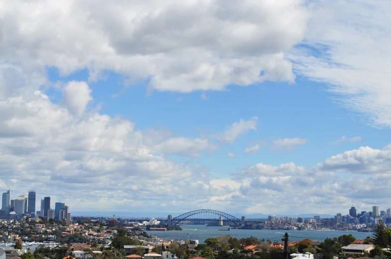 a view of a city from the top of a hill, inspired by Sydney Carline, pexels, partly cloudy sky, bay, 2 4 mm iso 8 0 0, tall bridge with city on top