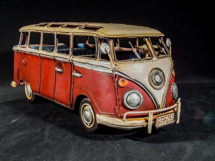 a red and white vw bus sitting on top of a black surface, by Richard Carline, made of wax and metal, stained antique copper car paint, extremely detailed frontal angle, rusted