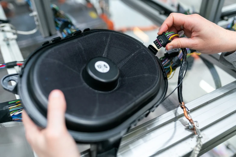 a close up of a person holding a speaker, by Matthias Stom, shutterstock, bauhaus, exploded parts assembly, engineering bay, featuring wires, car